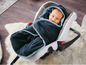 Ein Baby in einem Autositz, eingewickelt in einen blauen Fleece-Schlafsack mit Kapuze.