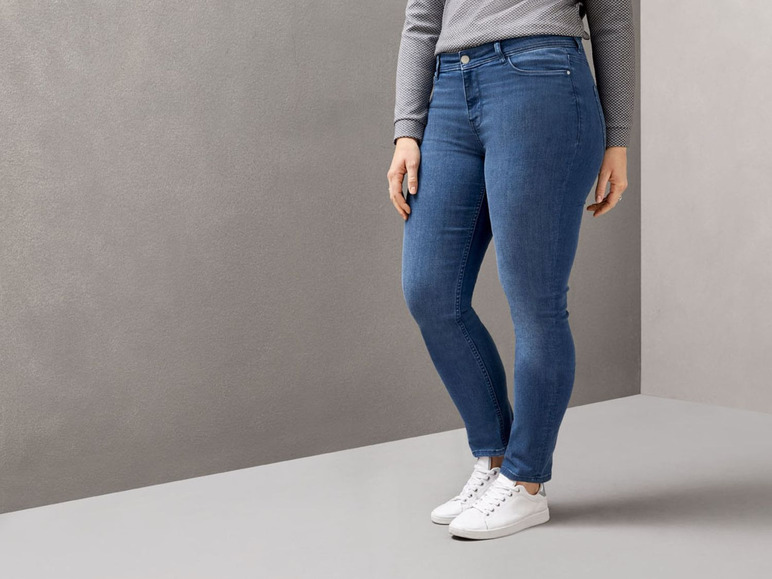 Eine Frau trägt eine enge Jeans und weiße Sneakers.