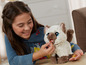 Ein Mädchen füttert ein interaktives Plüschkatzenspielzeug von FurReal Friends.
