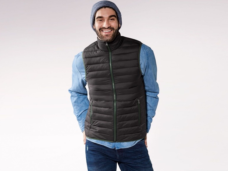 Ein Mann in einer schwarzen Daunenweste und blauen Jeans.