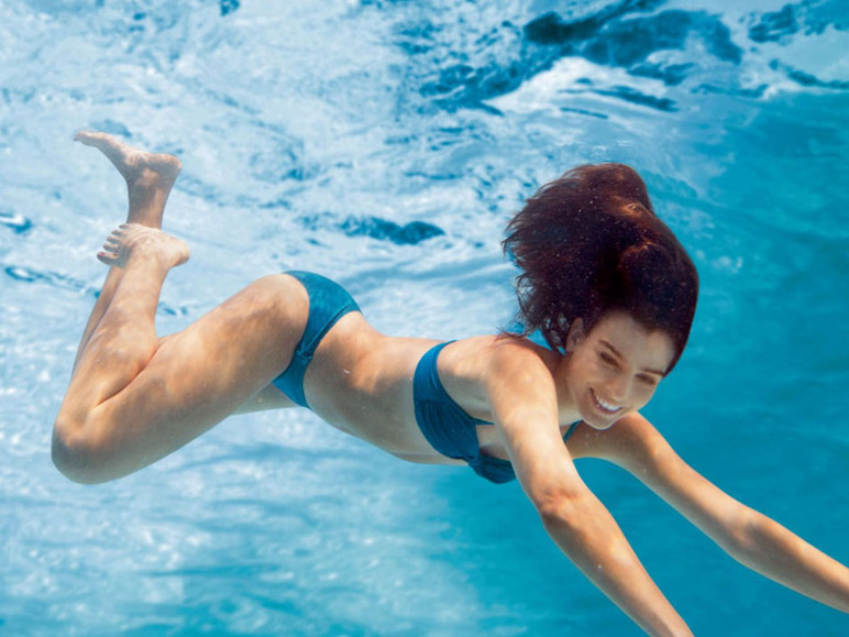 Eine Frau in einem blauen Bikini schwimmt unter Wasser.