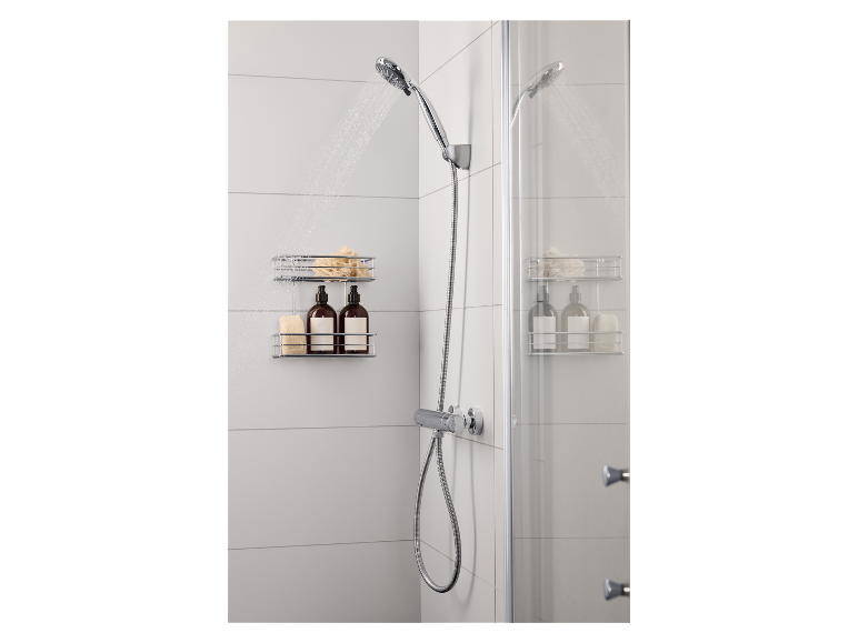 Dusche mit Handbrause, Duschablage mit Flaschen und Schwämmen in einem weiß gefliesten Badezimmer.