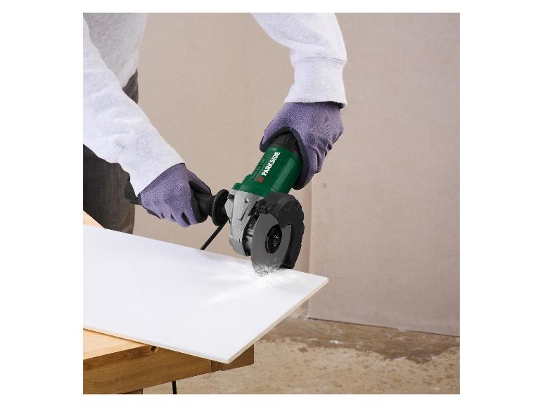 Person in Handschuhen schneidet eine weiße Platte mit einem grünen Winkelschleifer, der Funken erzeugt.