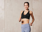 Eine Frau in einem schwarzen Sport-BH und blauen Leggings beim Sport.