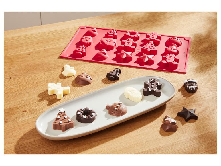 Weihnachtliche Schokoladenform und ein Tablett mit verschiedenen Schokoladenpralinen.