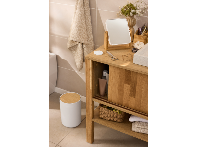 Badezimmerschrank mit Spiegel, Toilettenartikeln und Handtüchern in Naturholzoptik.
