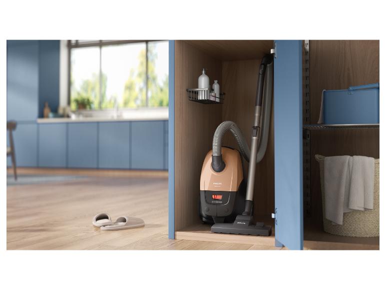 Staubsauger in einem Schrank verstaut, mit Hausschuhen auf Holzboden in einer Küche.