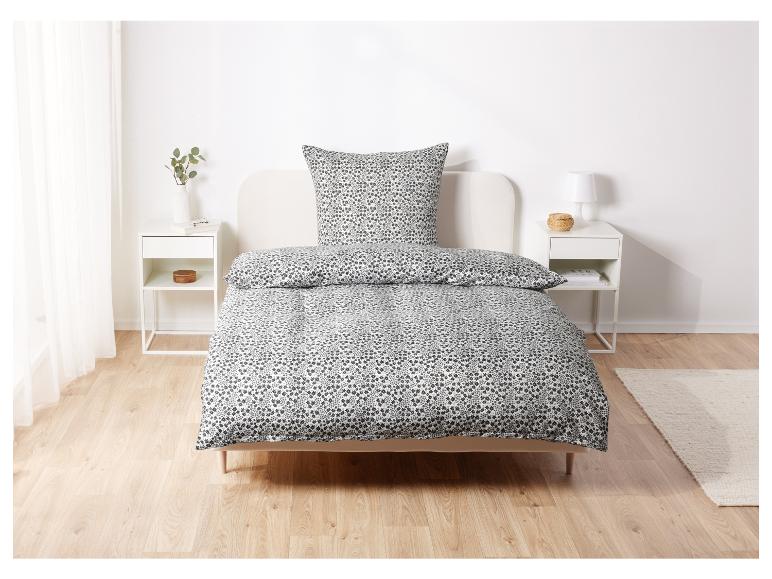 Ein Bett mit einem weißen Bettbezug mit einem kleinen schwarzen Blumenmuster.