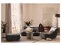 Wohnzimmer mit grauem Sofa, Sessel, Pouf und Holzkommode.