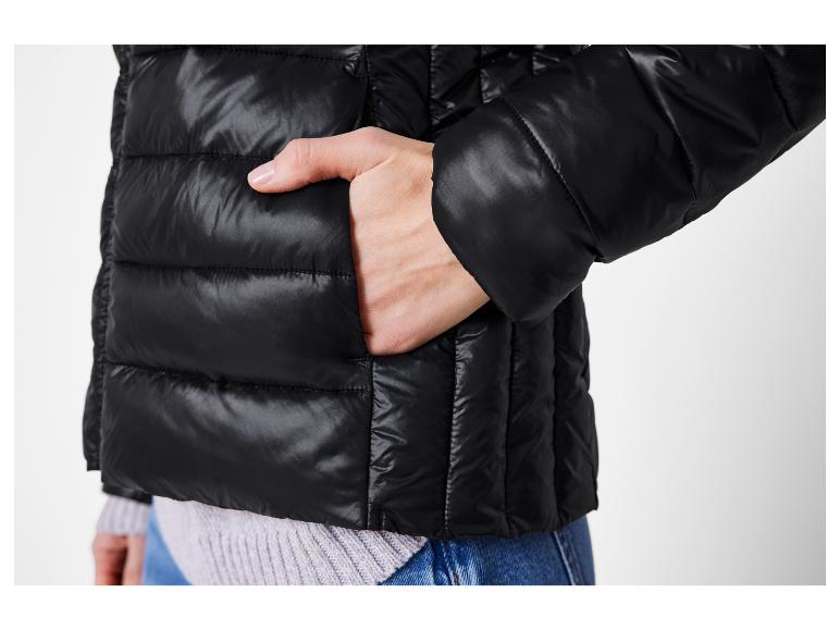 Schwarze Steppjacke mit Hand in der Tasche.