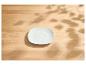 Weißer quadratischer Unterteller auf einem hellen Holztisch mit Blattschatten.