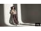 Frau in elegantem Pullover und brauner Hose, die sich an eine Wand lehnt.