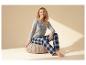 Frau in grauem Pyjama-Shirt und karierter Hose, Aufschrift „LETS STAY IN BED“.