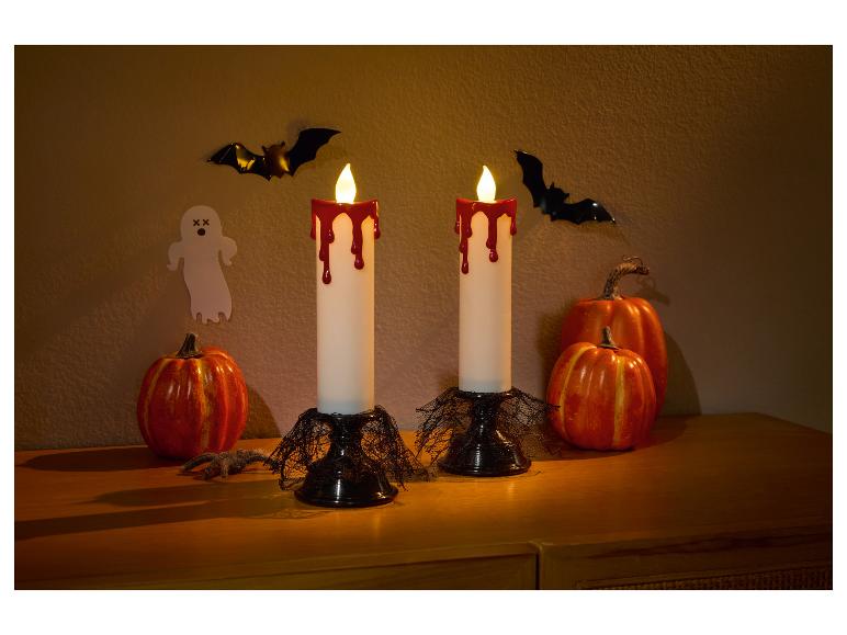Halloween-Dekoration mit zwei blutenden Kerzen, Kürbissen, Fledermäusen und einem Geist.