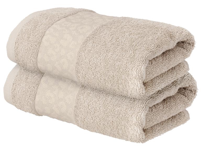 Zwei gefaltete beigefarbene Handtücher mit Muster, übereinander gestapelt.