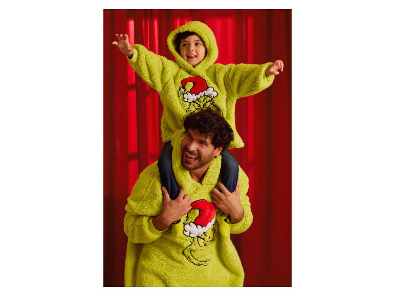 Vater und Sohn tragen passende Grinch-Hoodies, der Sohn auf den Schultern des Vaters