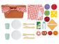 Ein Picknickkorb mit rot-weiß kariertem Tuch, Tellern, Bechern, Besteck und verschiedenen Spiellebensmitteln.
