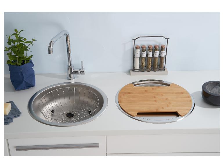 Küchenspüle mit Wasserhahn, Schneidebrett und Gewürzregal.