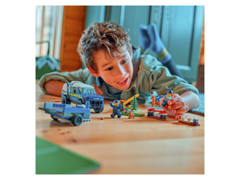 Ein Kind spielt mit LEGO City Polizeifahrzeugen und Figuren.