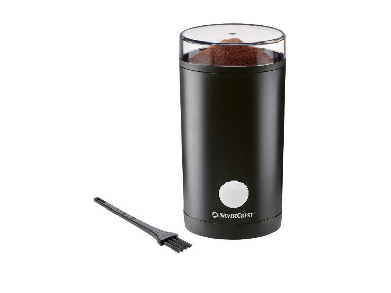 Schwarze elektrische Kaffeemühle mit transparentem Deckel, gefüllt mit gemahlenem Kaffee, und Reinigungsbürste.