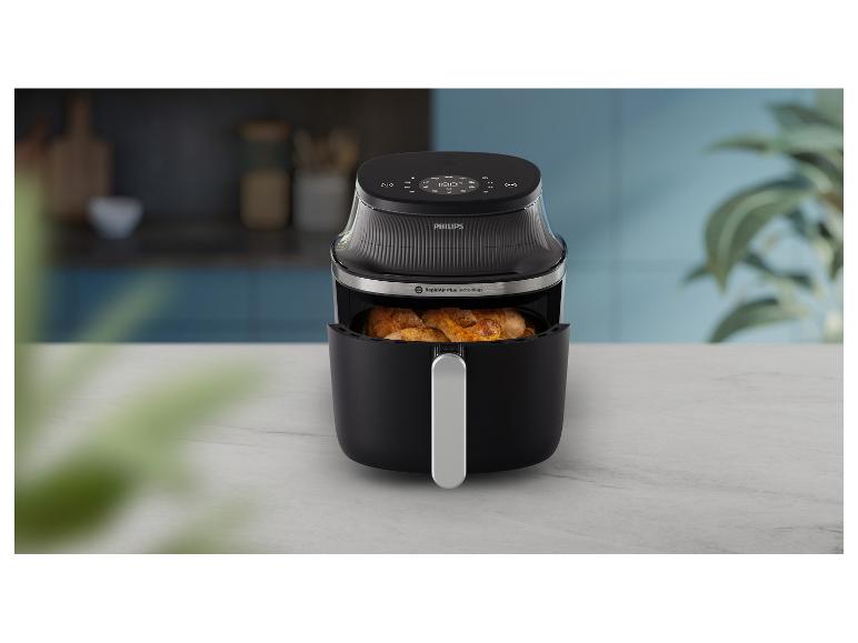 Schwarze Philips Heißluftfritteuse mit Hähnchen im Korb, auf einer Küchenarbeitsplatte.
