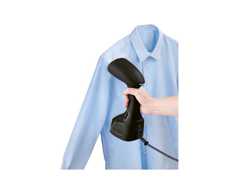 Ein Handdampfbügeleisen glättet ein blaues Hemd.