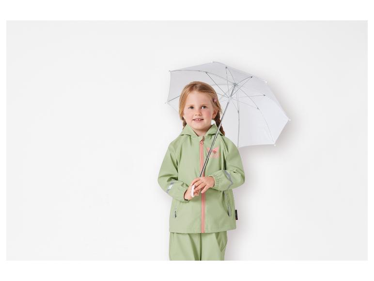 Ein Mädchen trägt einen grünen Regenmantel und eine Hose mit einem weißen Regenschirm.