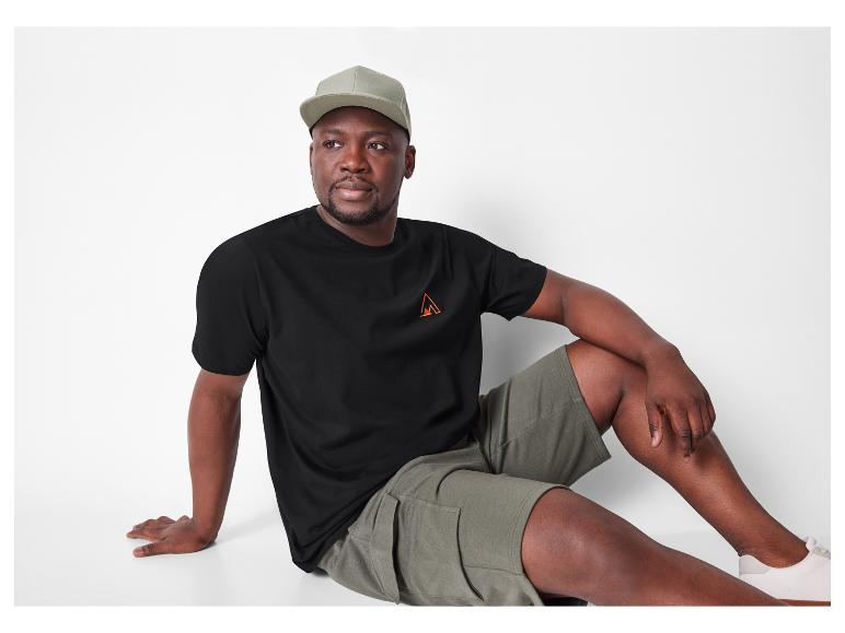 Ein Mann trägt ein schwarzes T-Shirt und grüne Shorts.