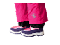 Rosa Kinder-Schneehose mit Schneeflocken-Emblem und lila-rosa Winterstiefeln.