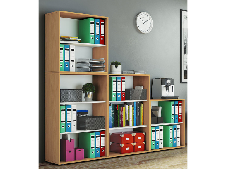 Ein Regal mit Ringordnern, Büchern, Boxen und einer Kaffeemaschine.