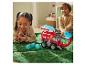 Zwei Kinder spielen mit einem Paw Patrol Fahrzeug und einer Figur auf einem grünen Teppich.