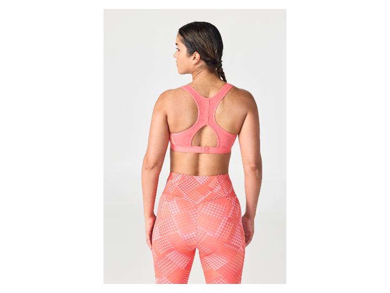 Frau von hinten in einem korallenrosa Sport-BH und gemusterten Leggings.