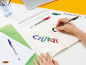 Eine Person schreibt „Cristal“ mit bunten Stiften in ein Notizbuch auf einem Schreibtisch.