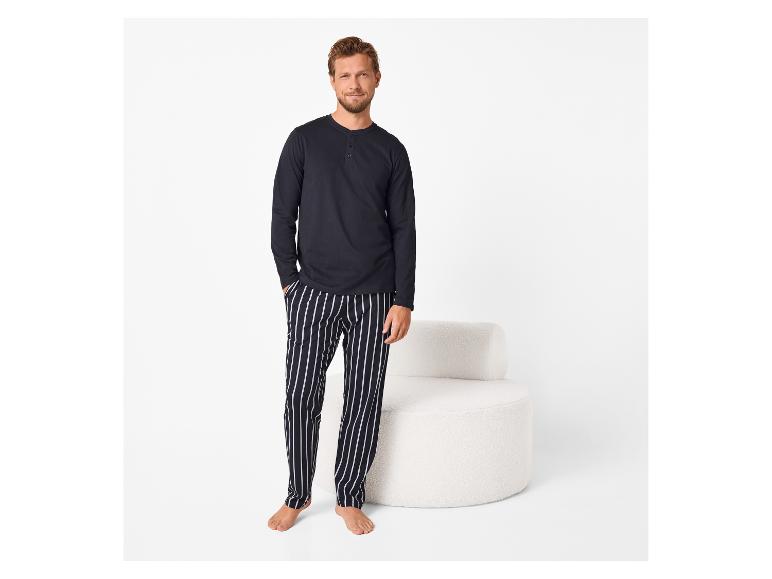 Mann in marineblauem Langarmshirt und gestreifter Pyjamahose.