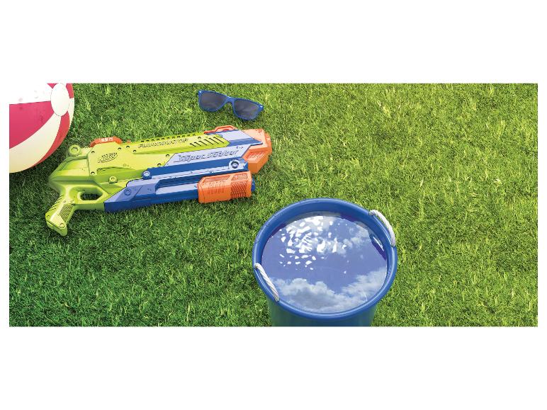 Wasserpistole, Strandball, Sonnenbrille und Eimer Wasser auf dem Gras.
