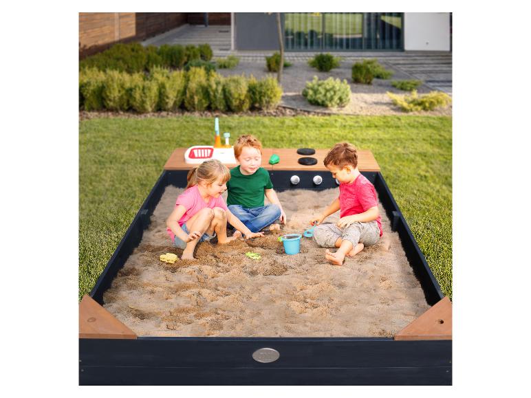 Kinder spielen in einem Sandkasten mit einer Outdoor-Matschküche.