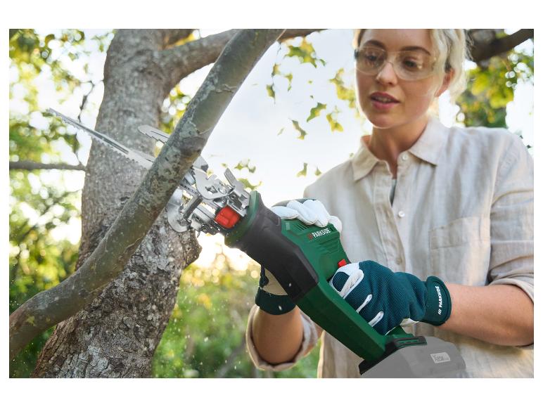 Eine Frau verwendet eine Akku-Kettensäge von Parkside, um einen Baumzweig zu beschneiden.