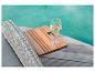 Glas Weißwein auf einem Holztisch am Pool.
