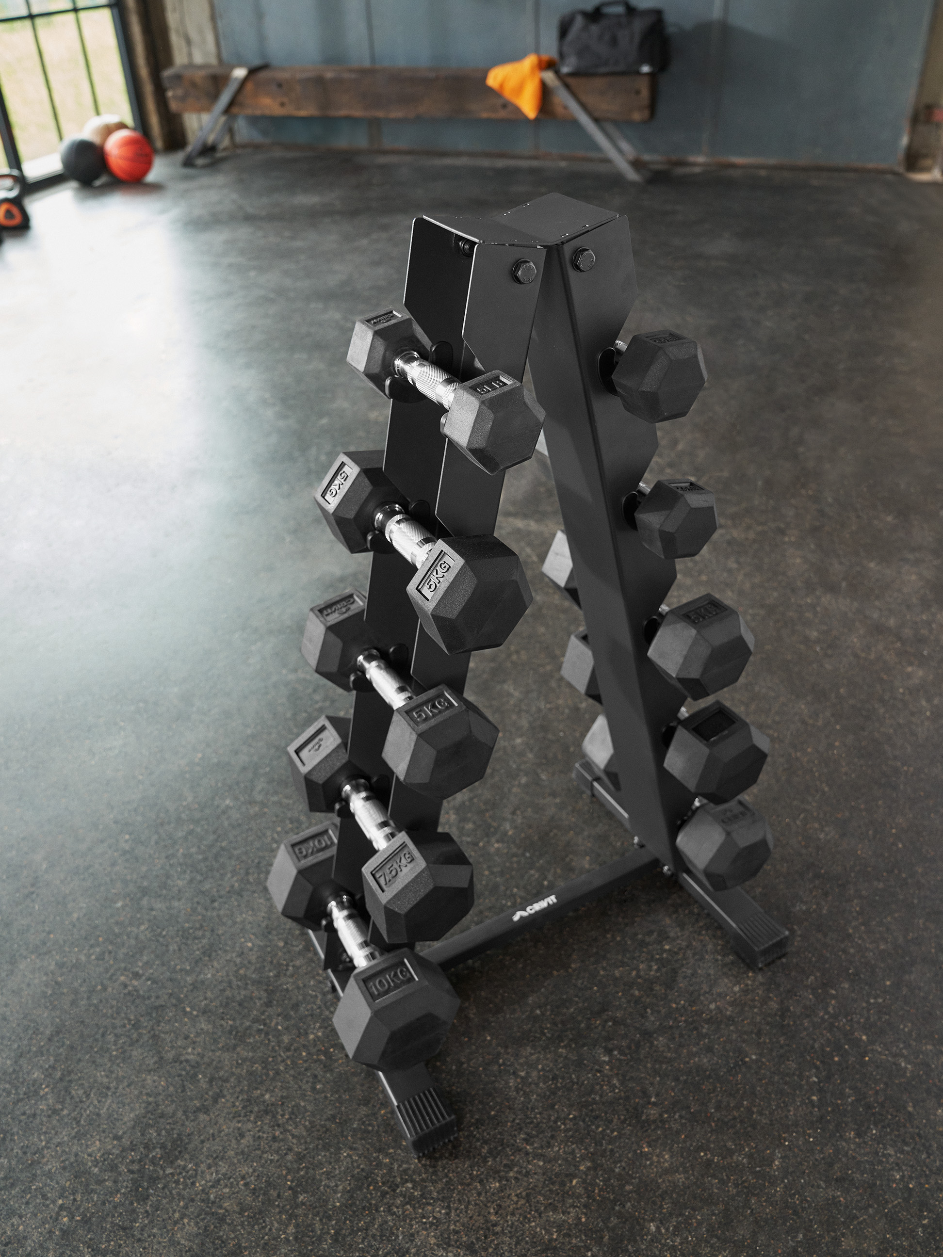 Ein schwarzer Hantelständer, gefüllt mit Hanteln unterschiedlichen Gewichts, in einem Fitnessstudio.