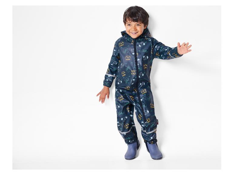 Ein Kind trägt einen blauen Regenoverall mit Tiger- und Elefantenmuster.