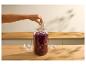 Hand legt ein Glasgewicht in ein Glas mit fermentiertem Rotkohl.