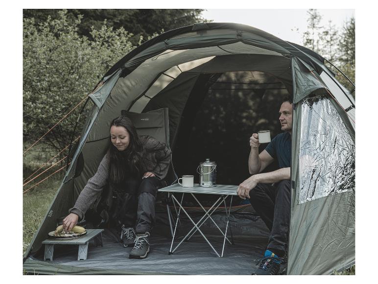 Zwei Personen sitzen in einem grünen Zelt mit einem Easy Camp Tisch und Stühlen.