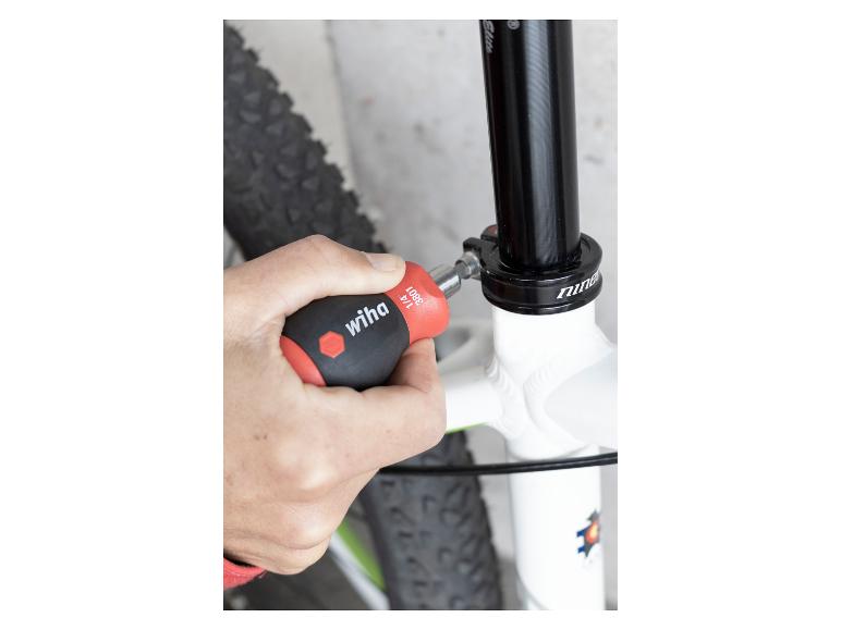 Person stellt Mountainbike-Sattelstütze mit einem Handschraubendreher ein.