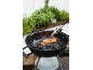 Holzkohlegrill mit Anzündhilfe, umgeben von Kräuterpflanzen.