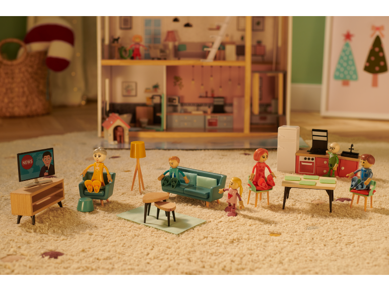 Puppenhaus mit Miniatur-Familienfiguren, Möbeln und einem Fernseher, der Nachrichten zeigt.