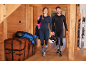 Paar in Ski-Thermo-Kleidung, mit Helmen und Skiern im Hintergrund.