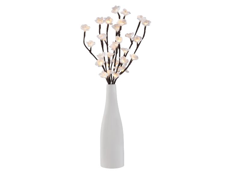 Weiße Vase mit beleuchteten Kirschblütenzweigen