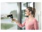 Frau reinigt ein Fenster mit Fensterreiniger und Sprühflasche.