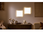 Zwei quadratische LED-Wandpaneele mit warmem Licht über einer Kommode im Wohnzimmer.