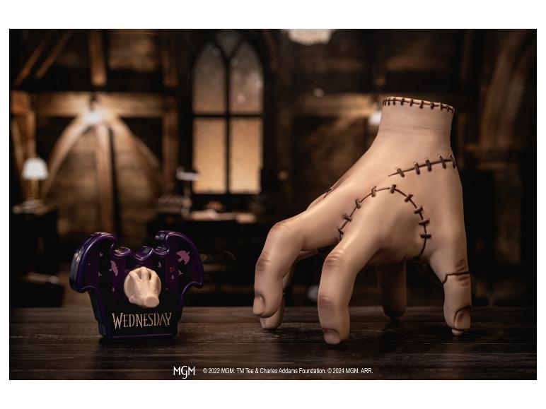 Handfigur und violetter Stiftehalter mit „WEDNESDAY“-Schriftzug auf Holztisch.
